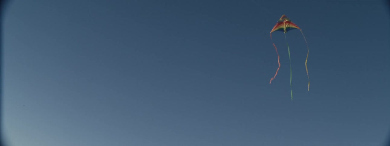 A boy is flying a kite high in the blue sky