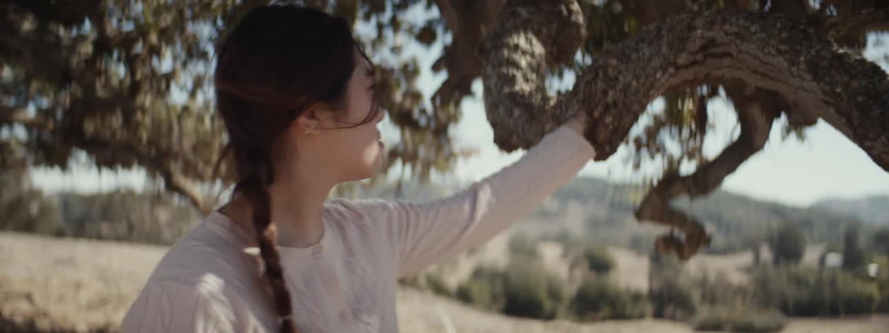 A woman moves her hand along the long tree branch