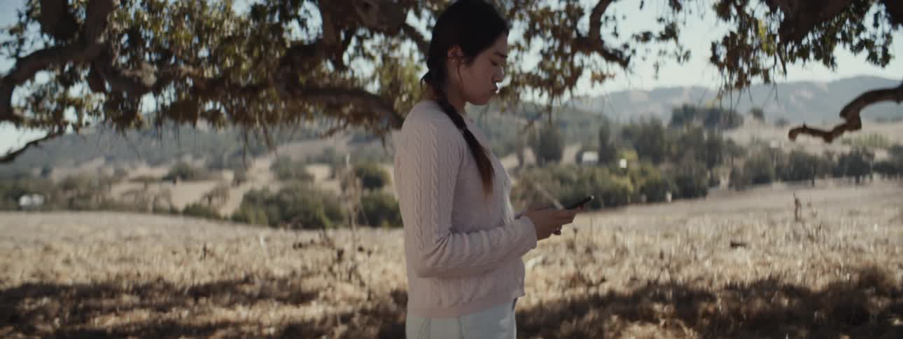 A woman uses her cell phone under the tree