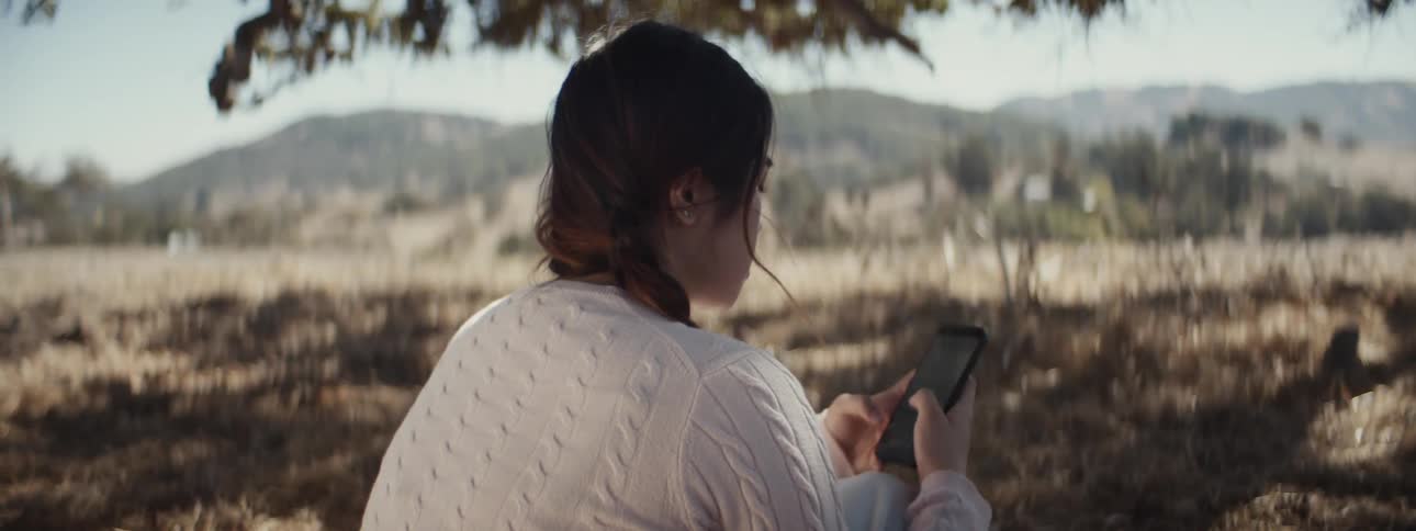 A woman is using her phone under the tree