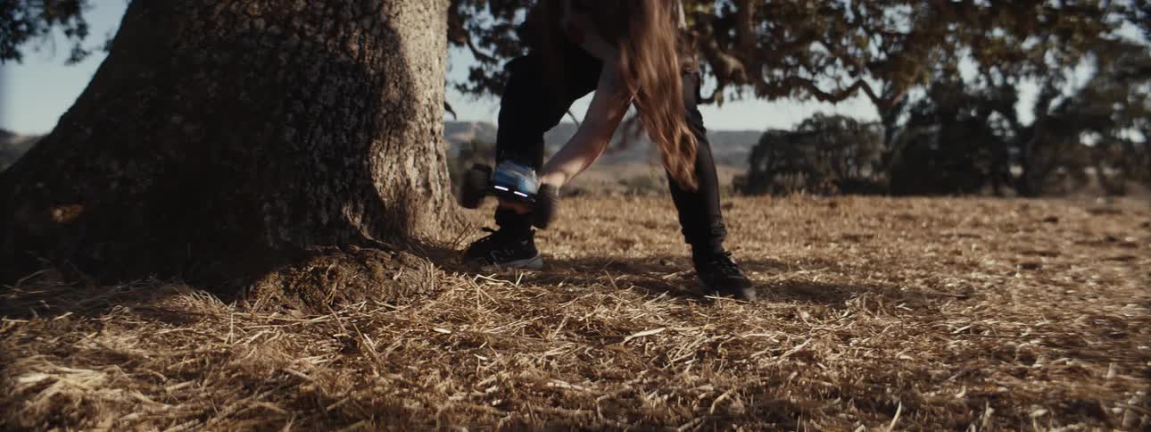 A girl drives her remote control car away from the tree