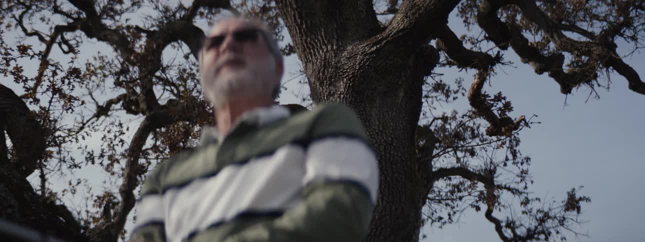 A man swings his golf club under the tree