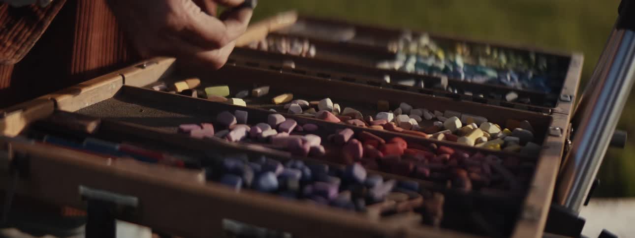 Hand of an illustrator picking up a box of crayons