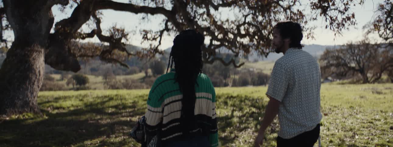 Man and a woman walking towards a tree in a forest