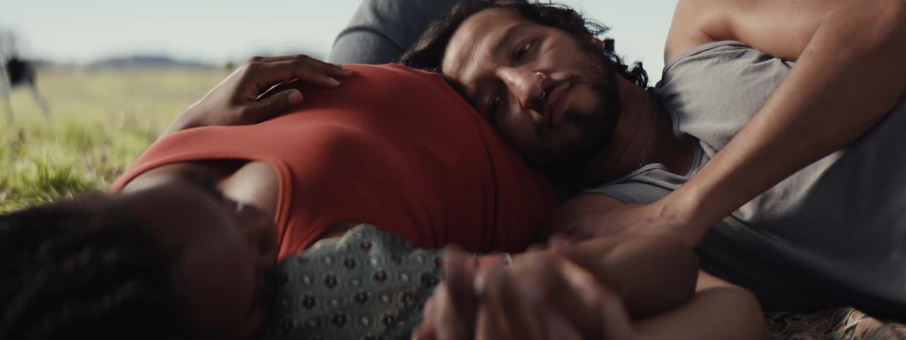 Man lying on his pregnant wifes belly in a field