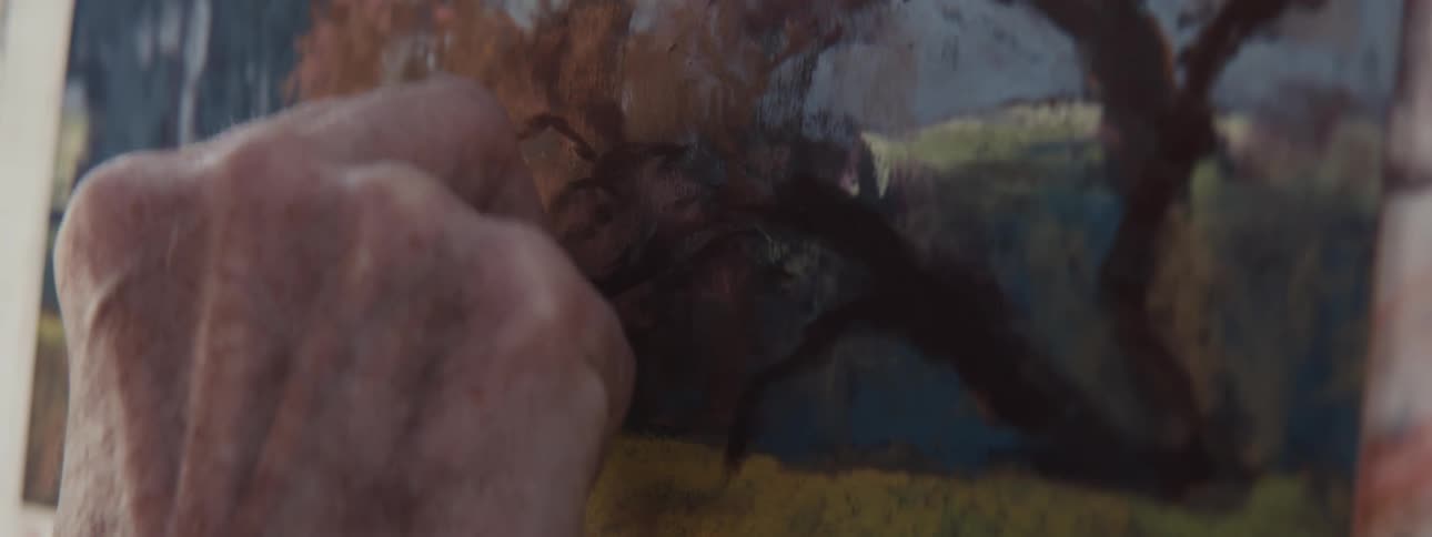 Hand of a painter painting a picture of a landscape