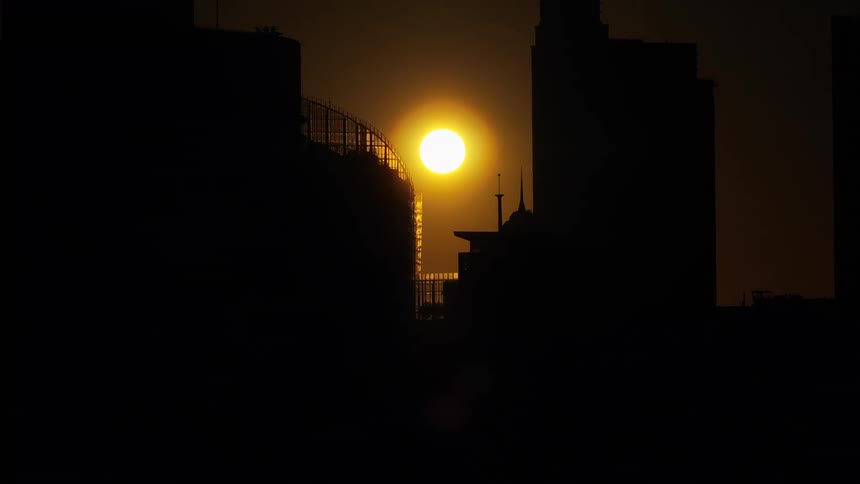Golden sun passing near a metropolis with the silhouette of buildings