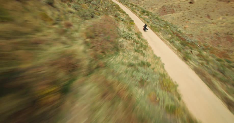 Person on a motorcycle traveling down a narrow road surrounded by canyons