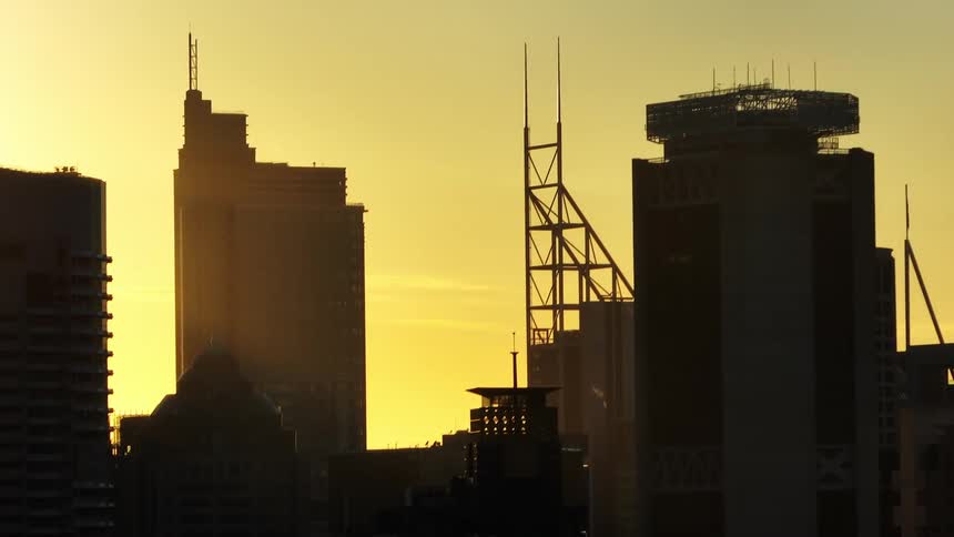 Aerial view of a few close up buildings in the city with an orange sunrise in the sky