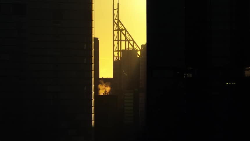 Silhouettes of buildings against a yellow sky