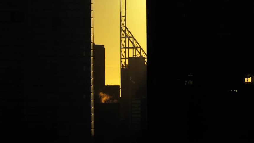 Buildings in a metropolis against a strong golden sun