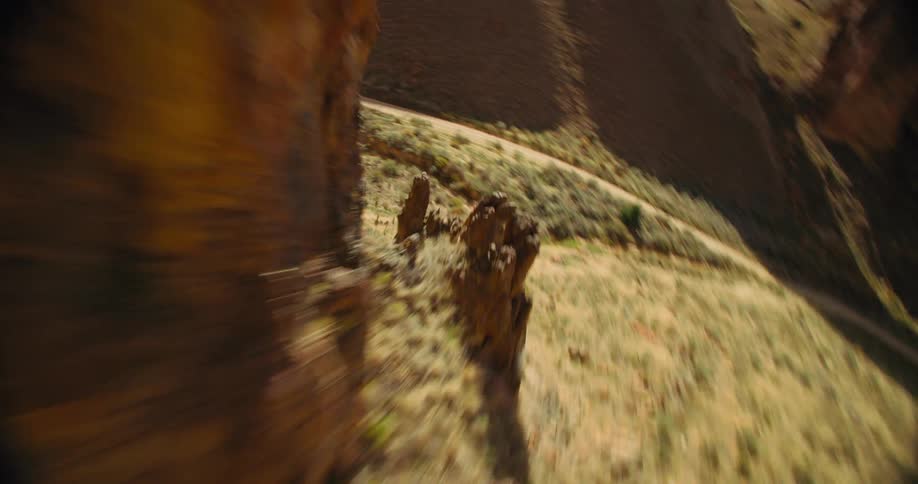 Aerial panorama of arid mountains revealing a narrow road at the base
