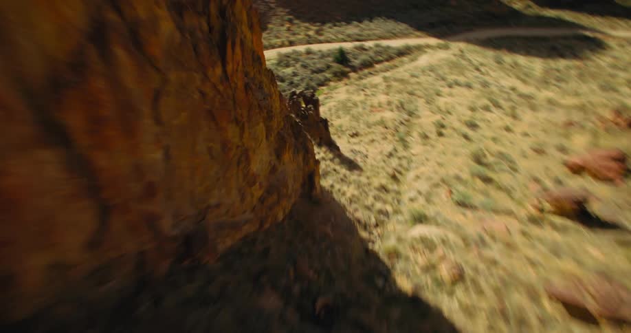An aerial view of a desert mountain descent with several rock formations and a dirt road