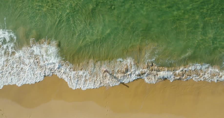 Aerial view of a person in the calm waters of a beach