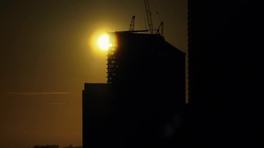 Buildings of a metropolis silhouetted against a golden sun