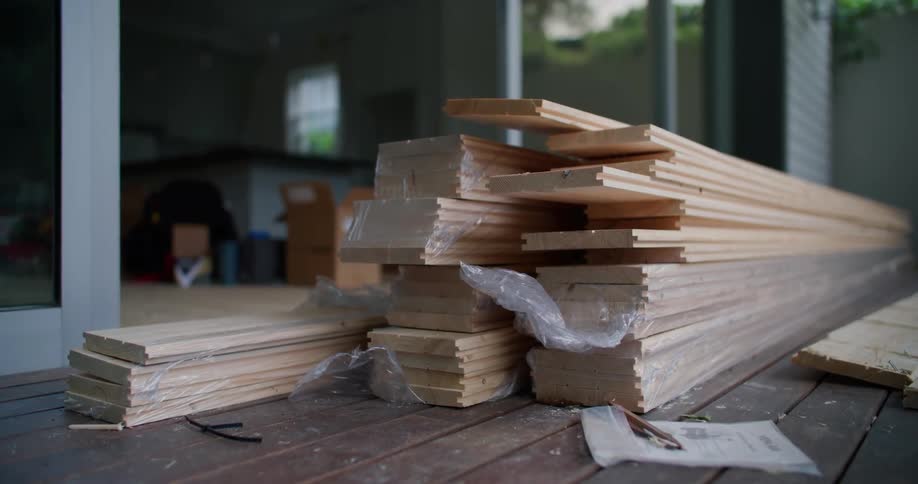 Stacks of construction lumber boards next to a house