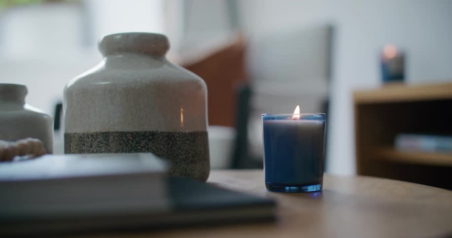 Lit candle in a blue jar on top of a coffee table