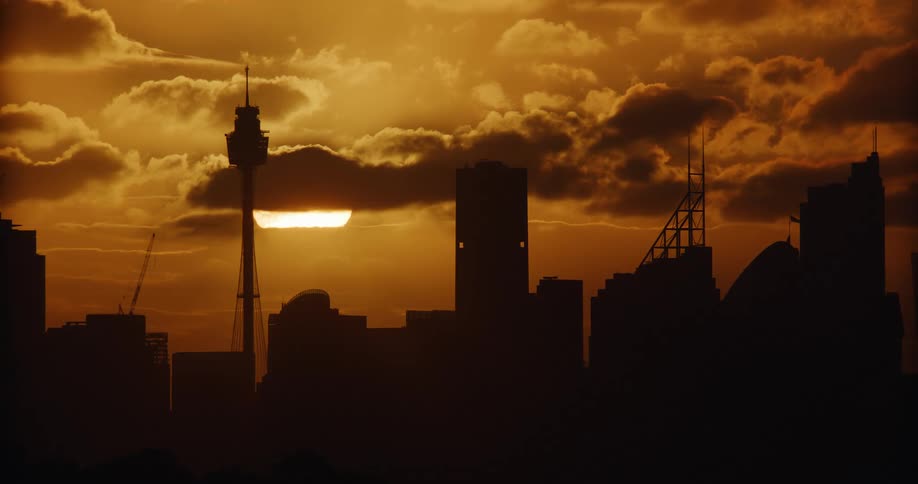 Scenery of skyscrapers in a metropolis against the golden sun on the horizon