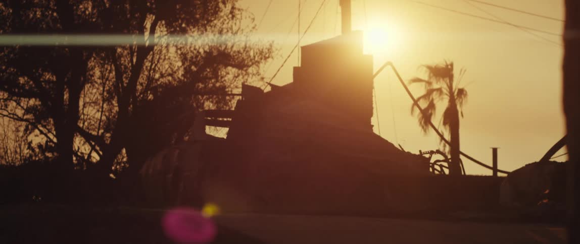 Golden sun cast reflections against a destroyed urban area
