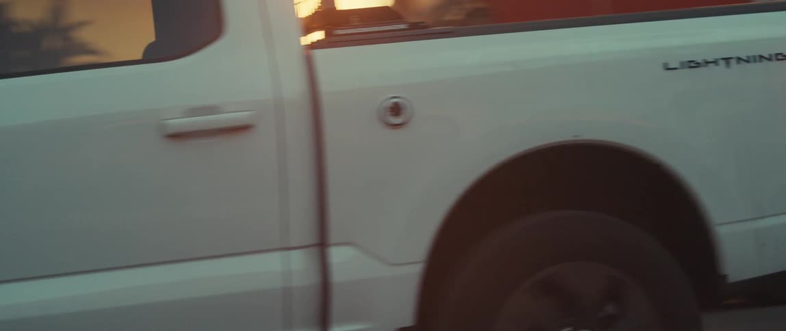 Truck drives past a firetruck parked in a residential neighborhood under a red tinted sky