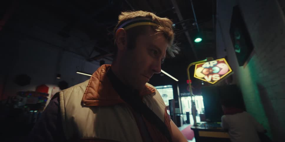 A close up of a young man wearing a colorful headband enjoying playing video games on an arcade machine