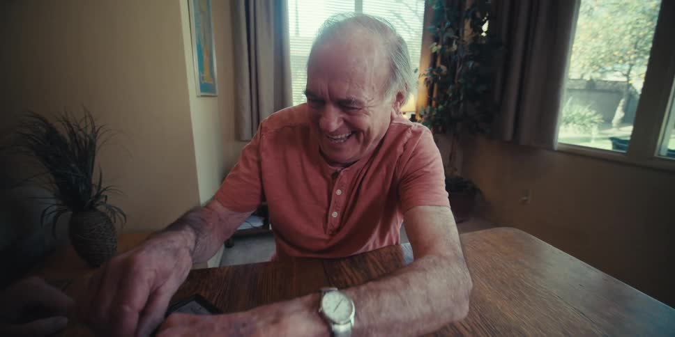 Elderly man being happy while playing chess with another person sitting at the table