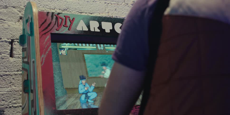 A man is playing a fighting game on the arcade machine