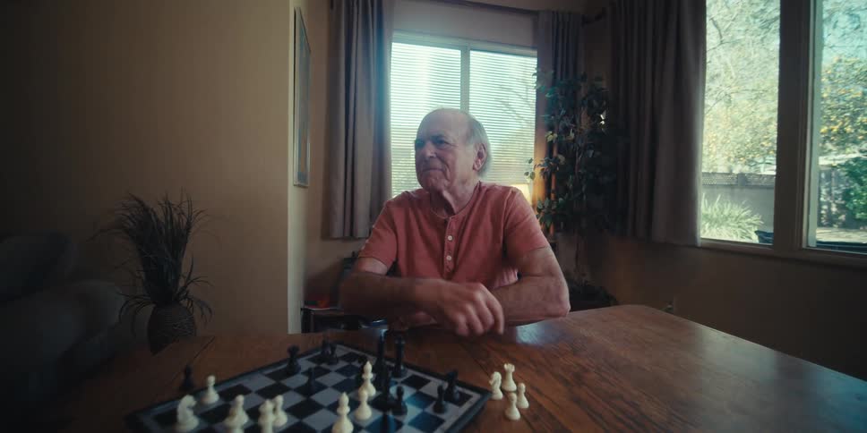Elderly man having fun playing chess sitting at the table