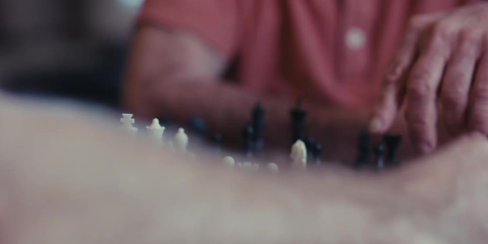 A close up of two peoples hands playing chess