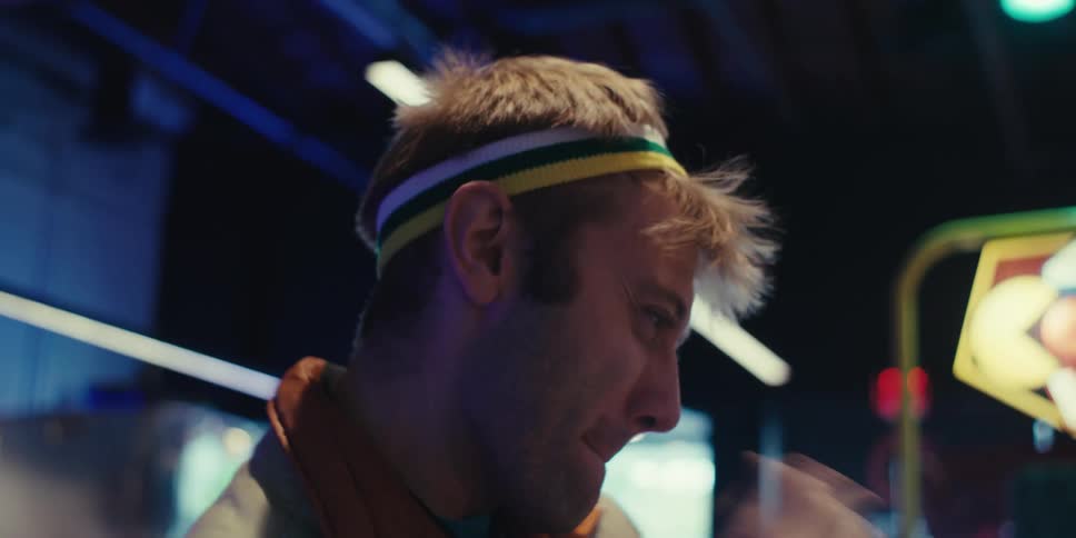 The face of a man with a headband looking at something in front of him and then celebrating