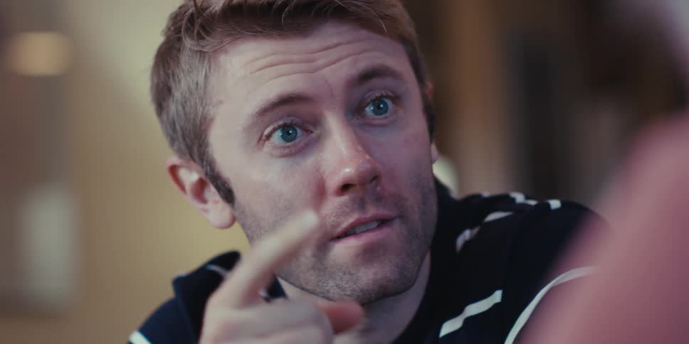 The face of a young man talking and pointing to someone in front of him