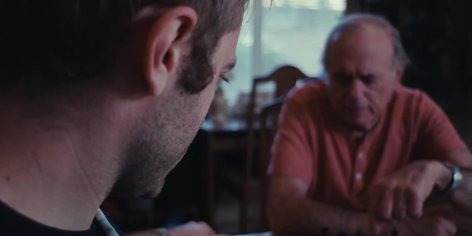 Elderly man and a young man playing chess sitting at a table