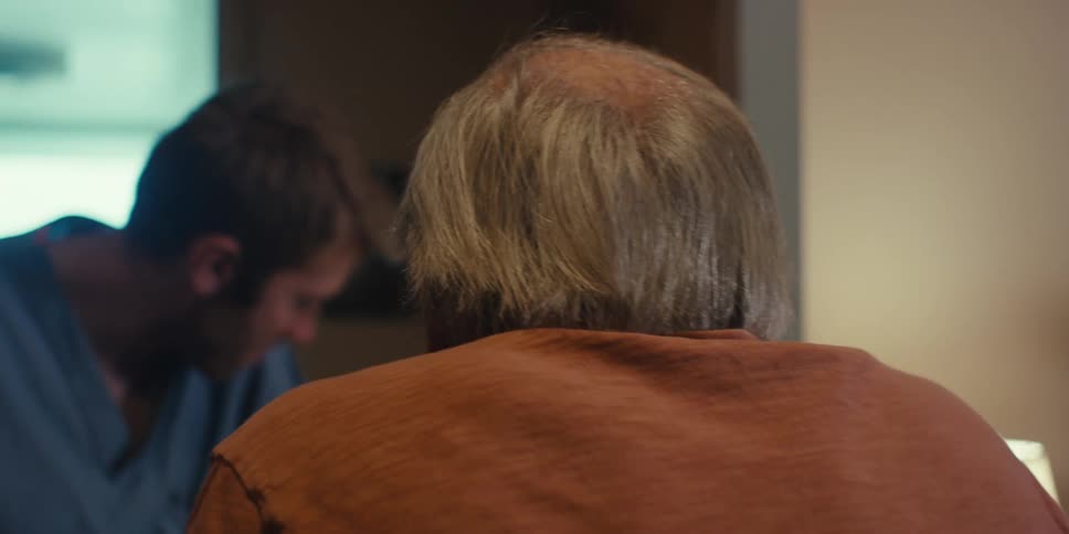 A home health aid is helping a man walk into a room