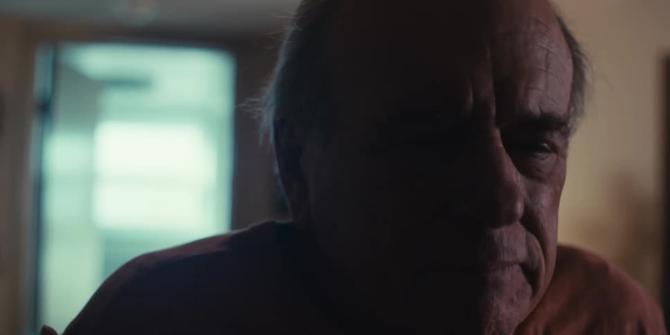 Close up of the face of an elderly man talking to someone else at home