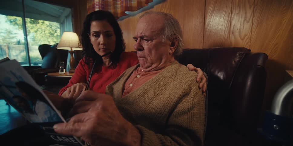Elderly man sitting next to scared daughter while reading medical paper