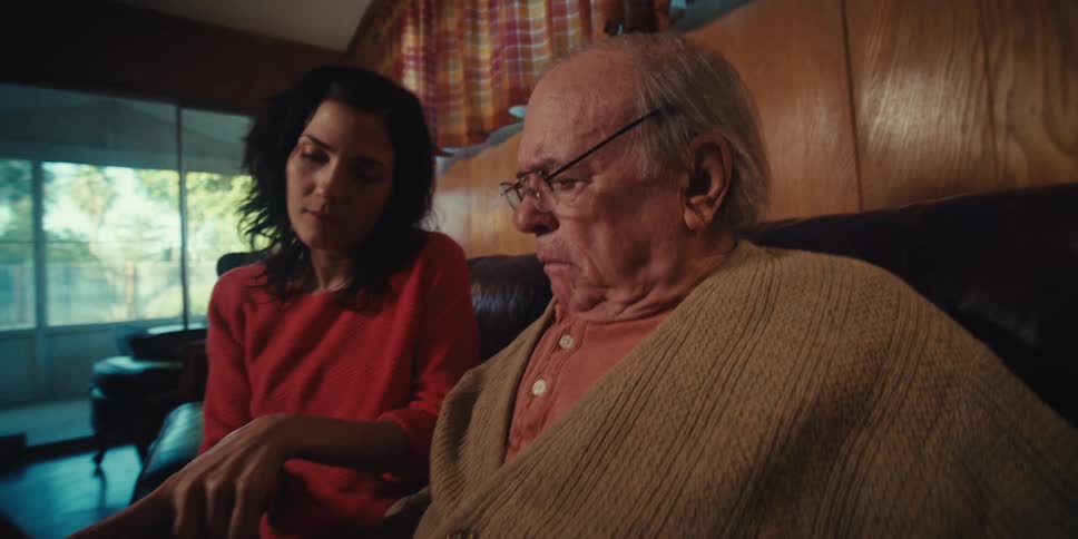 Daughter and elderly father looking at scans together sitting on the couch