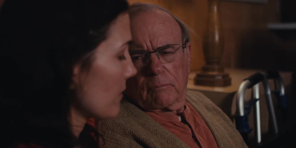 Elderly man and his daughter discuss a brochure with a medical professional while sitting at home