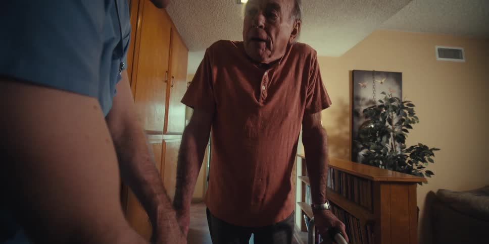 Nurse accompanying an elderly man in a hallway