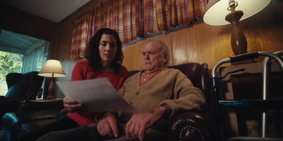 A home healthcare aid hands a piece of paper to a shocked man