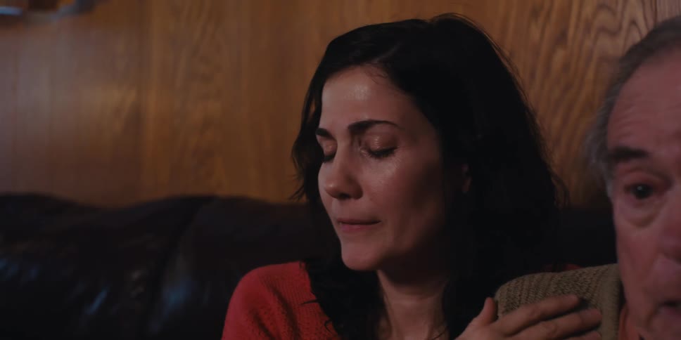Daughter comforting elderly father who is crying on the couch