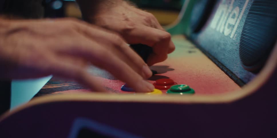 Pair of hands of a person playing an arcade machine