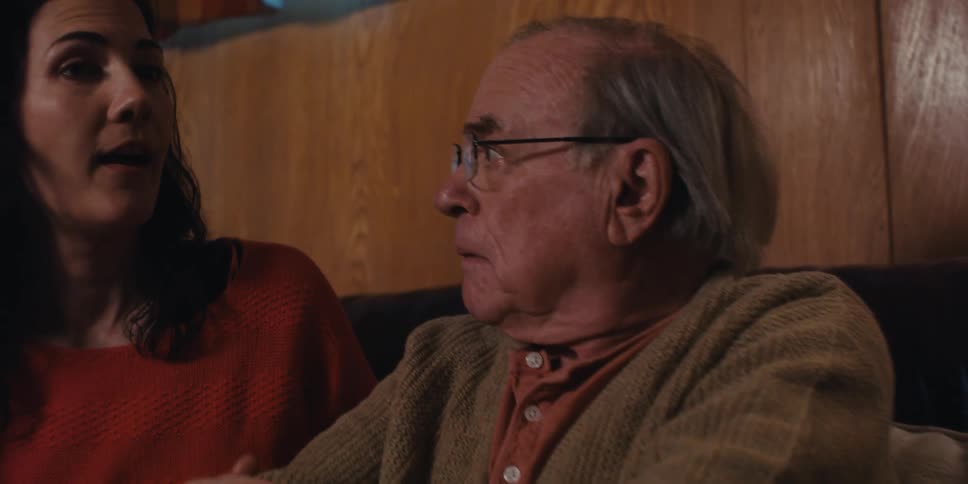 An elderly man listening as two young people talk to each other at home