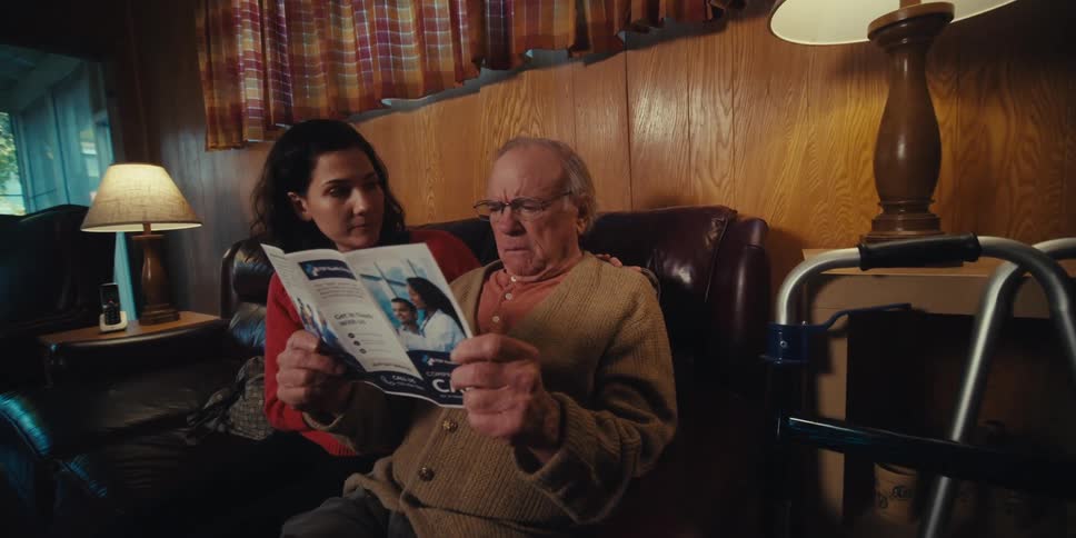 A woman and a male nurse explaining the contents of a brochure to an elderly man at home