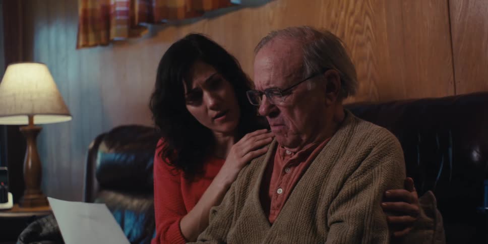 Elderly man sitting next to his daughter looking at a document