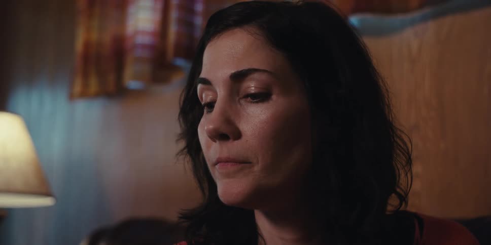 The face of a worried woman who is holding another persons arm while they are sitting