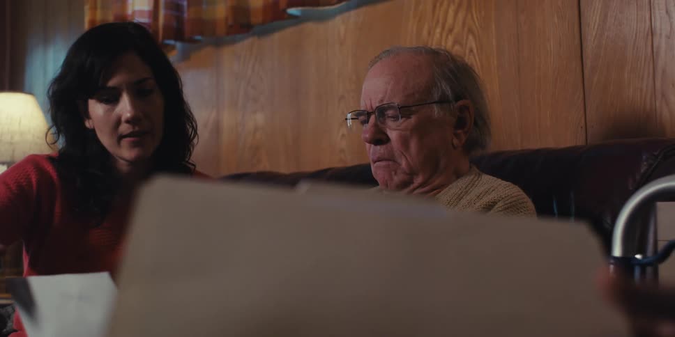 Daughter next to elderly father who is looking at medical reports