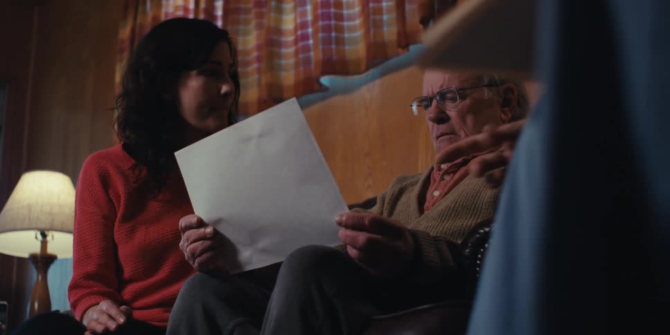 A woman and a male nurse explaining the contents of a document to an elderly man at home