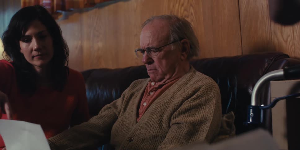 Nurse delivering a report to an elderly man who is sitting on the couch next to his daughter