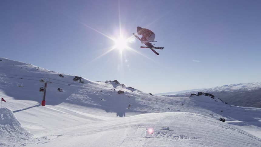 A person jumping and twisting on skis off a man made hill