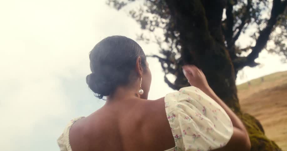 A clip of a lady standing beside a tree